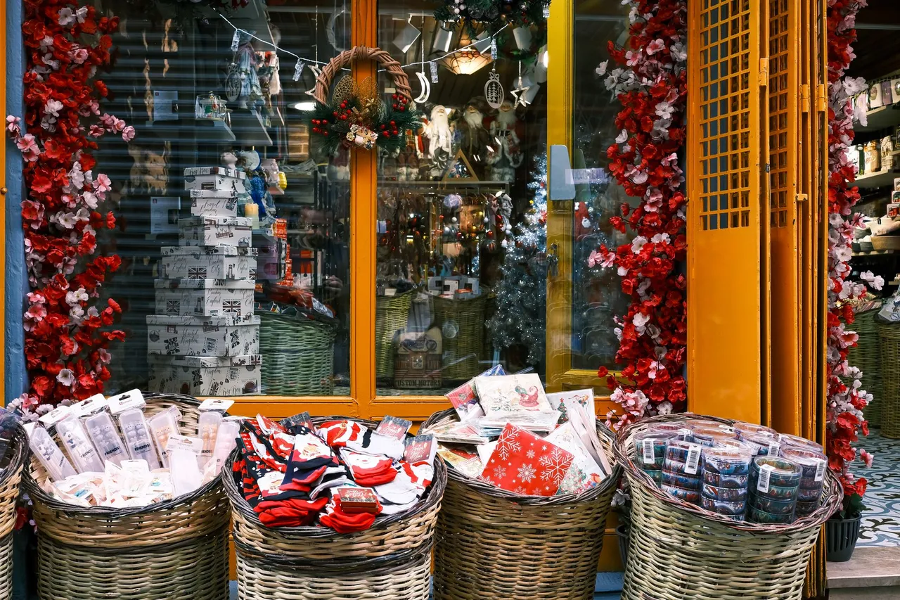 A festive storefront display featuring baskets of wrapped Christmas gifts and vibrant decorations.