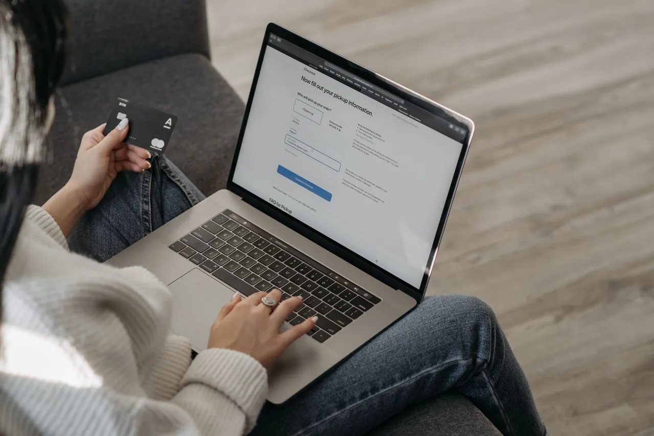 Close-up of a woman using a laptop for online shopping and holding a credit card in hand.