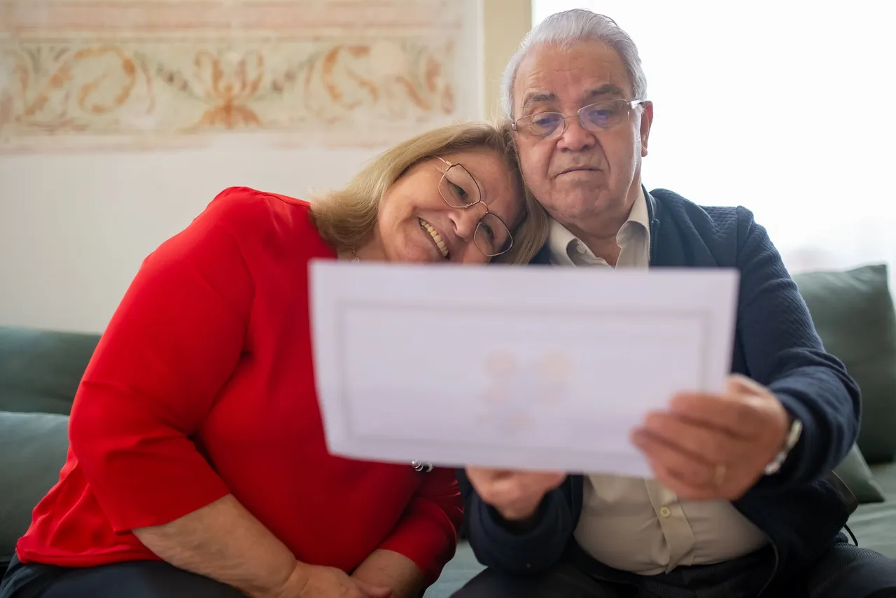 Elderly couple reviewing financial documents together at home in Portugal.