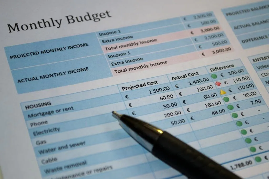 Printed monthly budget sheet with a pen, used to review recurring expenses.